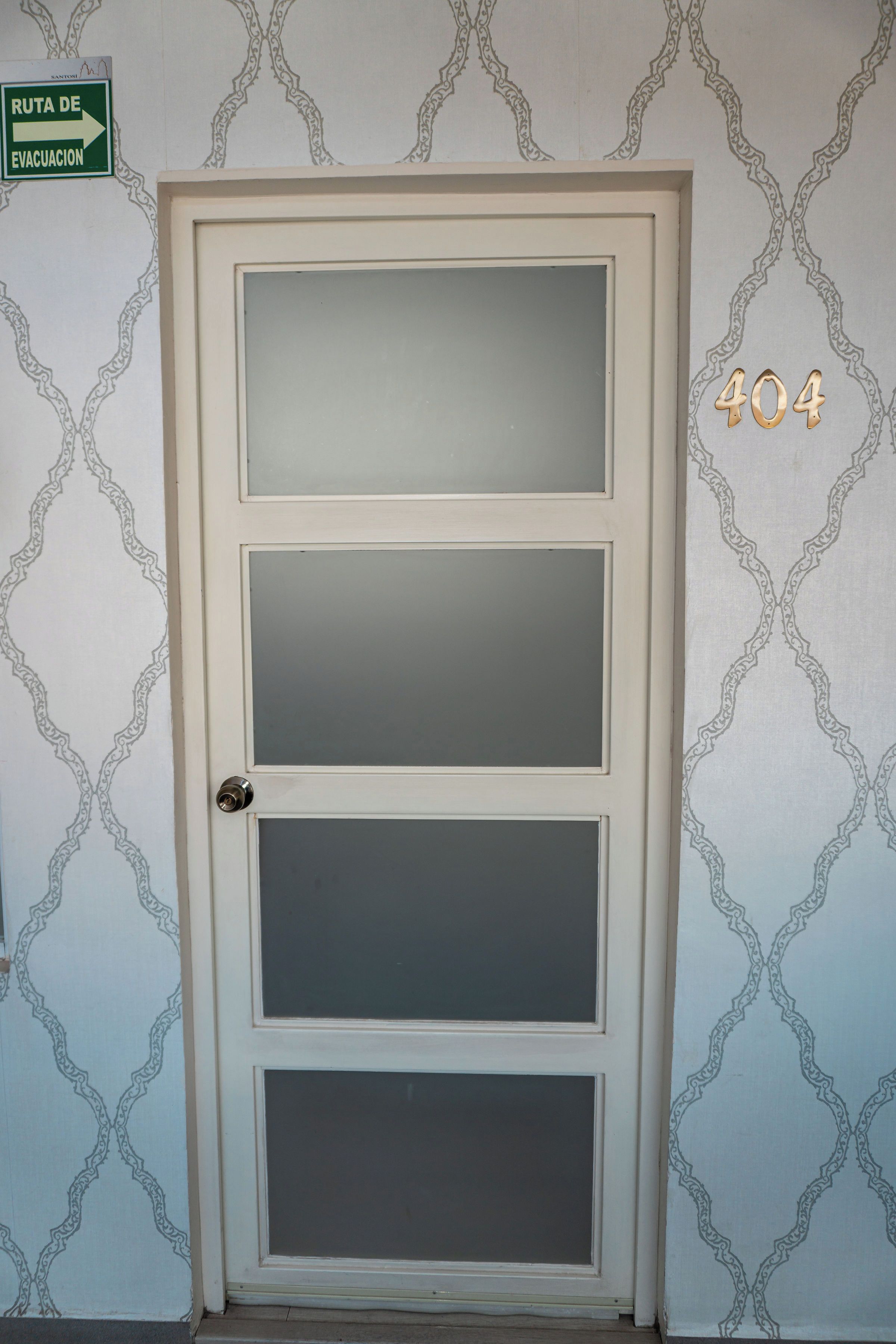 A door with frosted glass panels and a metal number '404' sign on the wall.