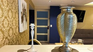 A room with a large decorative vase, a white pedestal, and a framed picture on the wall. - Hotel Santosi (San Luis Potosí)
