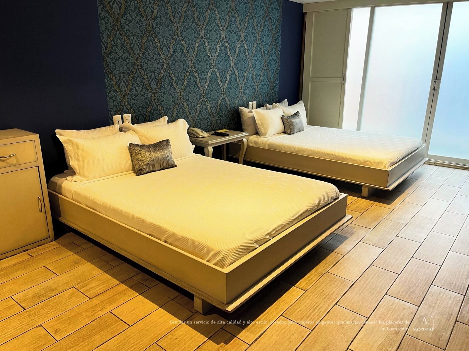 A hotel room with two beds, a nightstand, a desk, and a wardrobe.