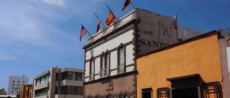 Un hôtel avec une enseigne indiquant « HÔTEL SANTO » et plusieurs drapeaux sur le toit.