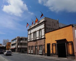 Un hotel con un cartel que dice "HOTEL SANTO" y varias banderas en el techo.