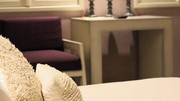 A hotel room with a bed, a chair, and a small table with a candle.