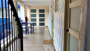 A corridor with patterned tiles, a staircase, and a door with a number. - Hotel Santosi (San Luis Potosí)