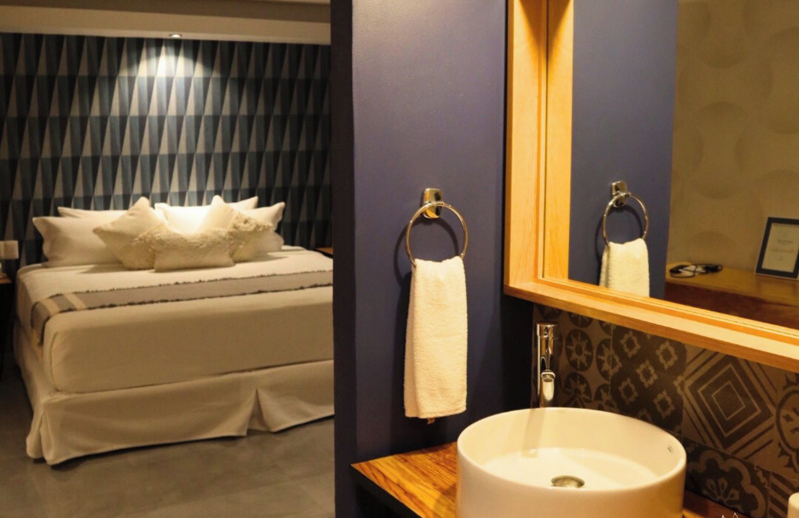 Une chambre d’hôtel avec un lit, une salle de bain avec un lavabo et un miroir.