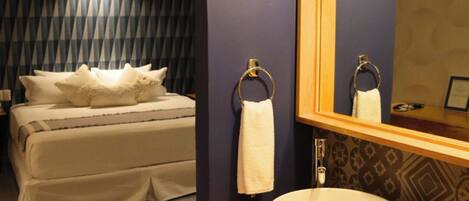 Une chambre d’hôtel avec un lit, une salle de bain avec un lavabo et un miroir.