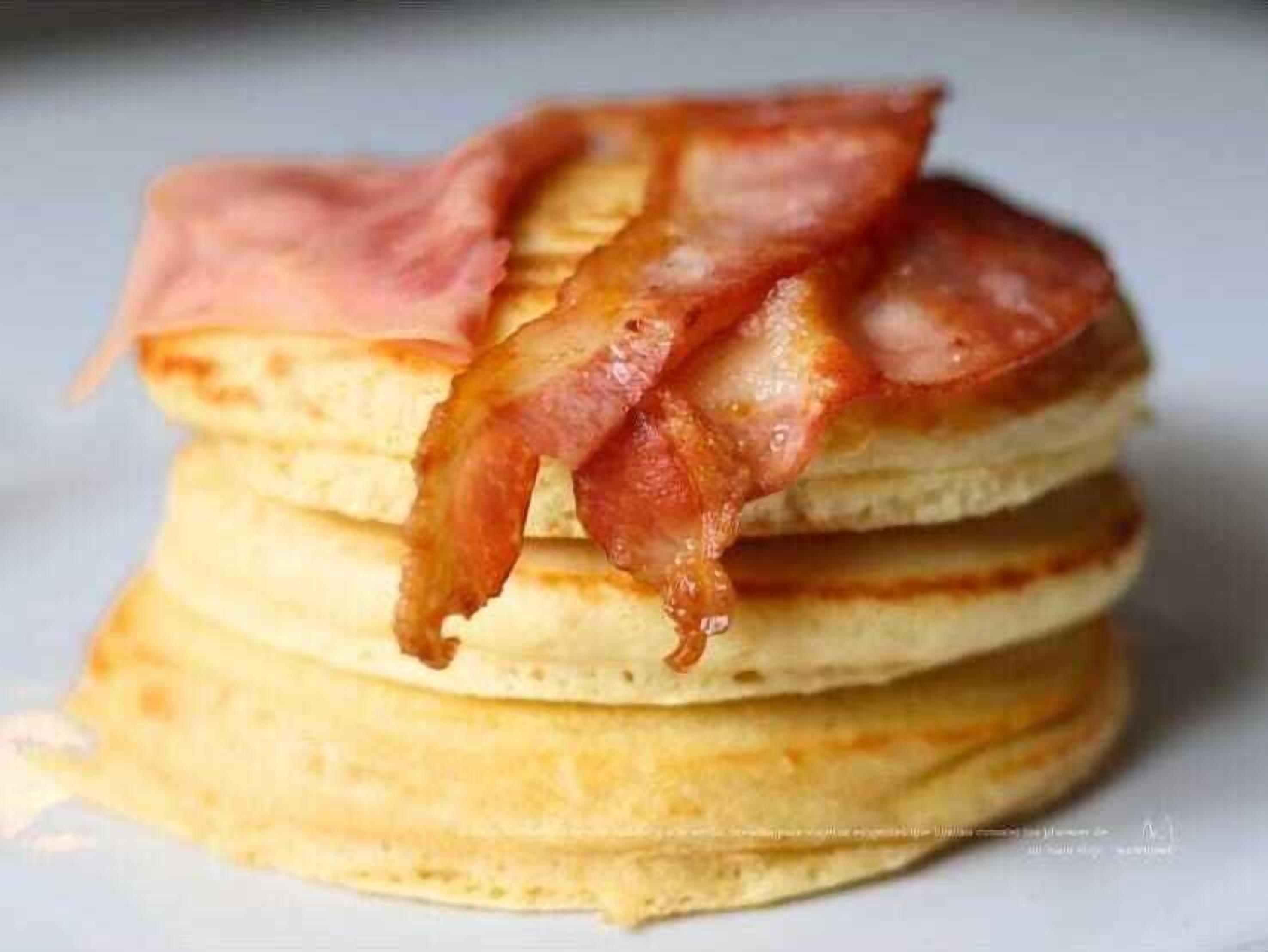 Een stapel pannenkoeken met spek erop.