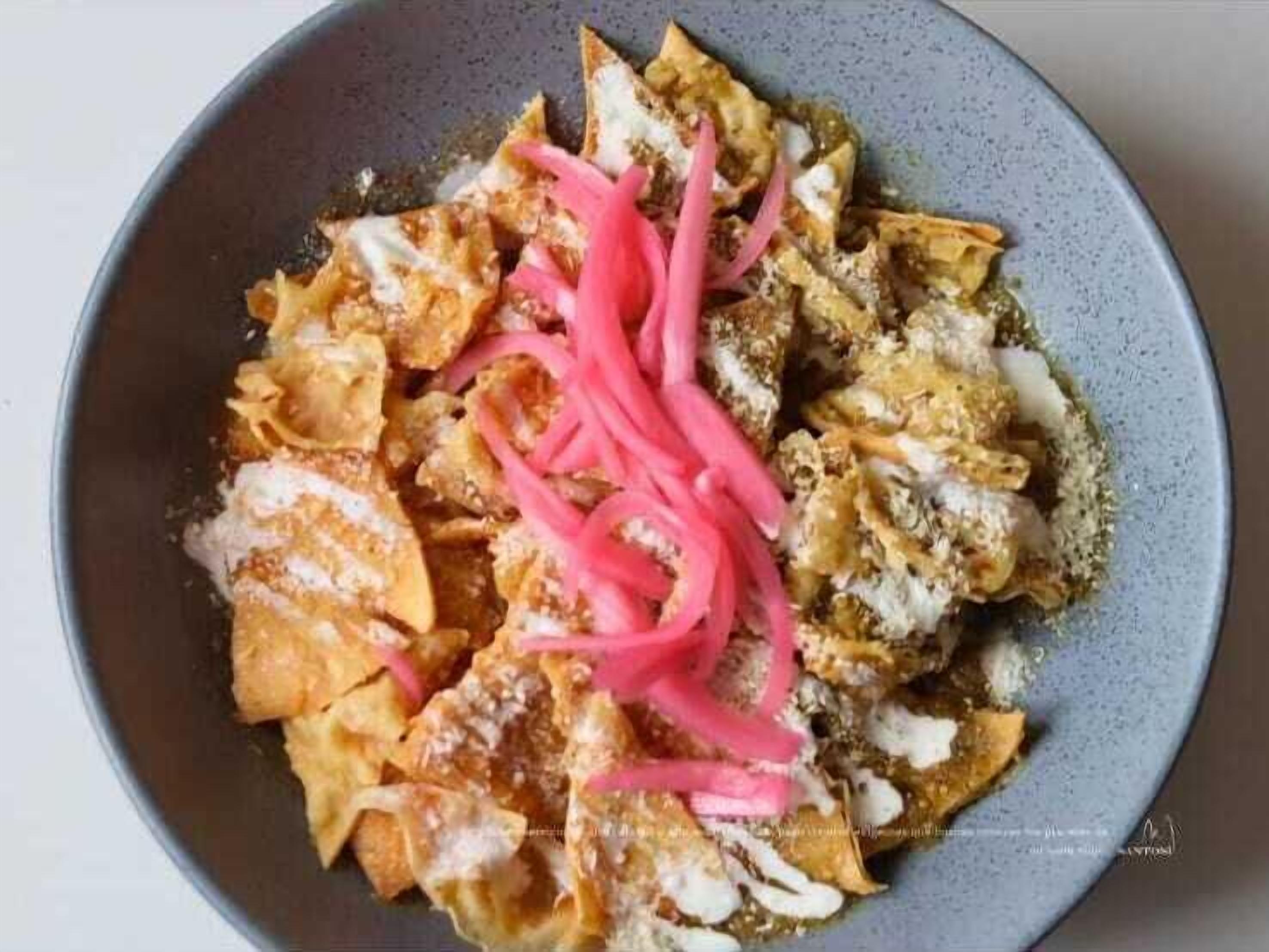 En skål nachos med ost, creme fraiche og pink syltede løg.