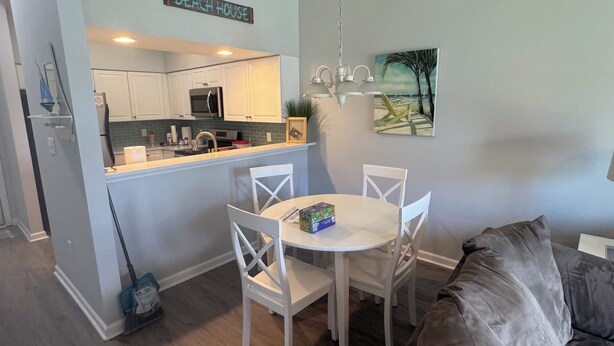 Una sala de estar moderna con comedor, una cocina al fondo y un cartel que dice "BEACH HOUSE".