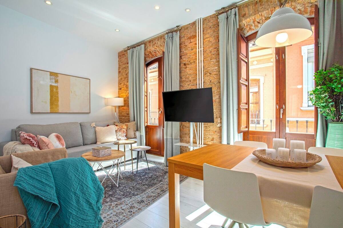 Uma sala de estar moderna com sofá, mesa de centro e área de jantar com mesa e cadeiras.