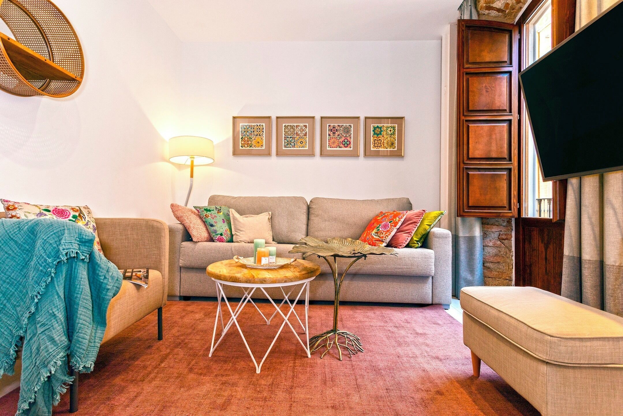 Uma sala de estar com sofá, mesa de centro redonda, abajur e televisão.