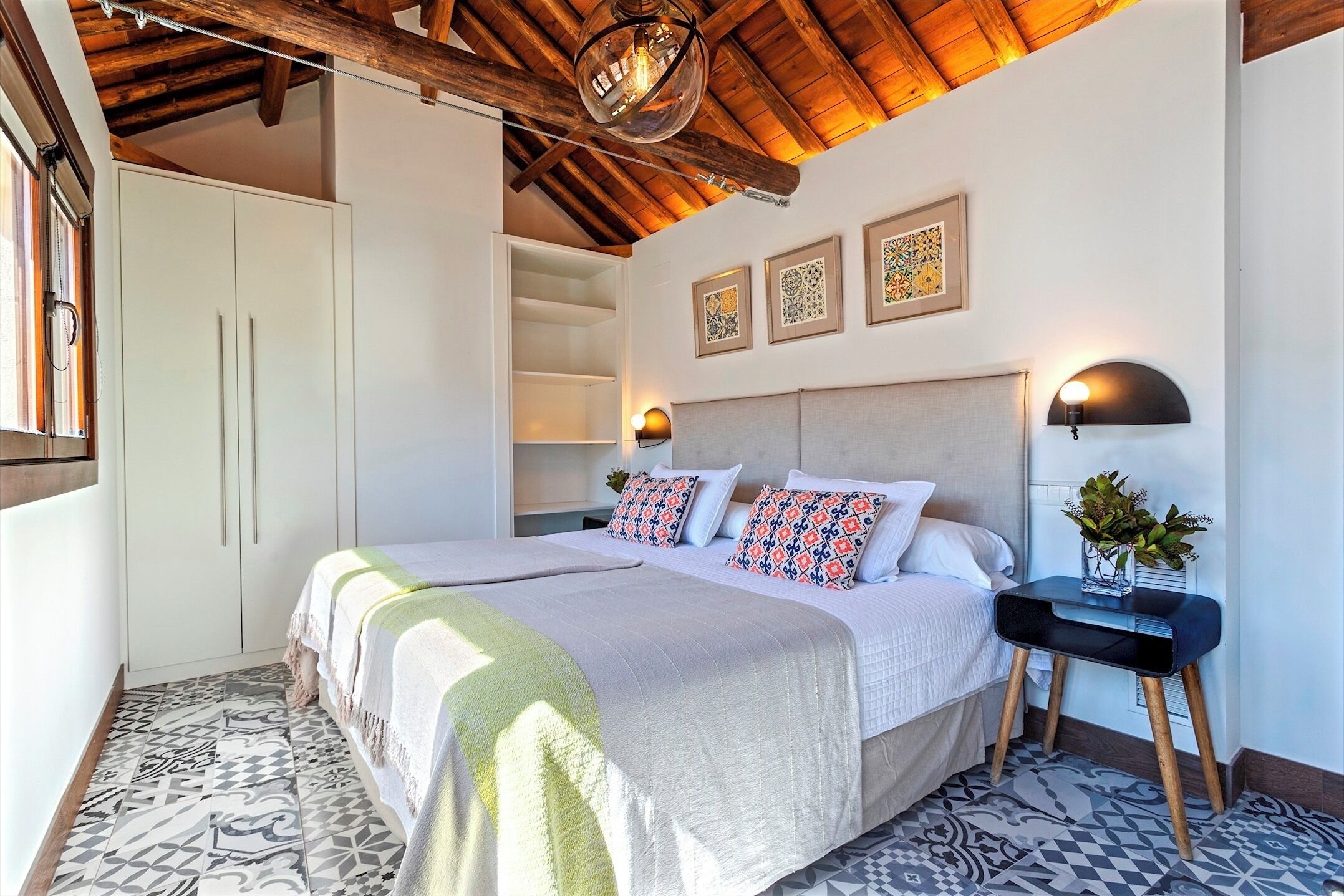 Une chambre avec un grand lit, une table de chevet avec une lampe et une armoire.