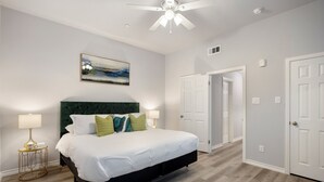 A bedroom with a bed, nightstands, a ceiling fan, and a door. - 1BR The Raven Flats B! Hermann Park! Med Center! (Houston)