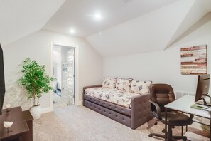 A cozy bedroom with a bed, a desk, a chair, and a potted plant. - Coastal Comfort | 4BR Beach Retreat with Beach Views +  ShortWalk to Shore! (Pass Christian)