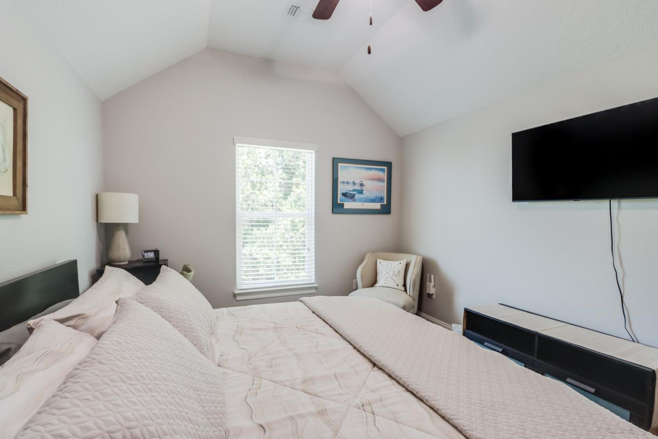 A bedroom with two beds, a window with blinds, a TV, and a painting on the wall.