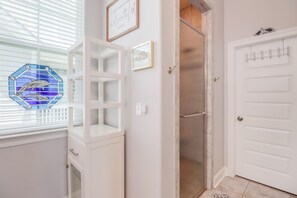A hallway with a white door, a glass door, and a wall-mounted shelf with a framed quote. - Coastal Comfort | 4BR Beach Retreat with Beach Views +  ShortWalk to Shore! (Pass Christian)