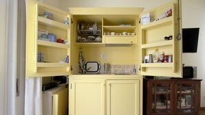 Una cocina compacta con armarios abiertos, un microondas y un refrigerador pequeño.