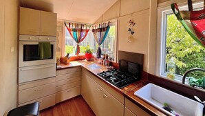 A kitchen with a stove, oven, and sink. There are cabinets and a window with curtains.