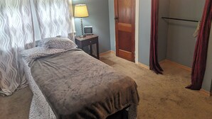 A bedroom with a bed, a nightstand, a lamp, a television, and a door. - 2-bedroom apartment with balcony view and walking distance balloon rally (Wellsville)