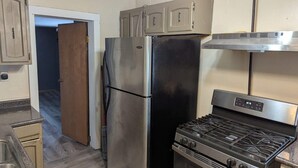 A compact kitchen with a stainless steel refrigerator, a gas stove, and wooden cabinets. - 2-bedroom apartment with balcony view and walking distance balloon rally (Wellsville)