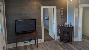 A living room with a television on a wooden stand, a fireplace, and a ceiling fan. - 2-bedroom apartment with balcony view and walking distance balloon rally (Wellsville)