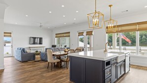 Une cuisine spacieuse dotée d’un grand îlot central, de planchers en bois et de luminaires modernes.