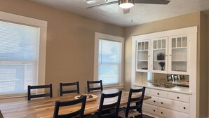 A dining area with a wooden table, black chairs, and a ceiling fan.