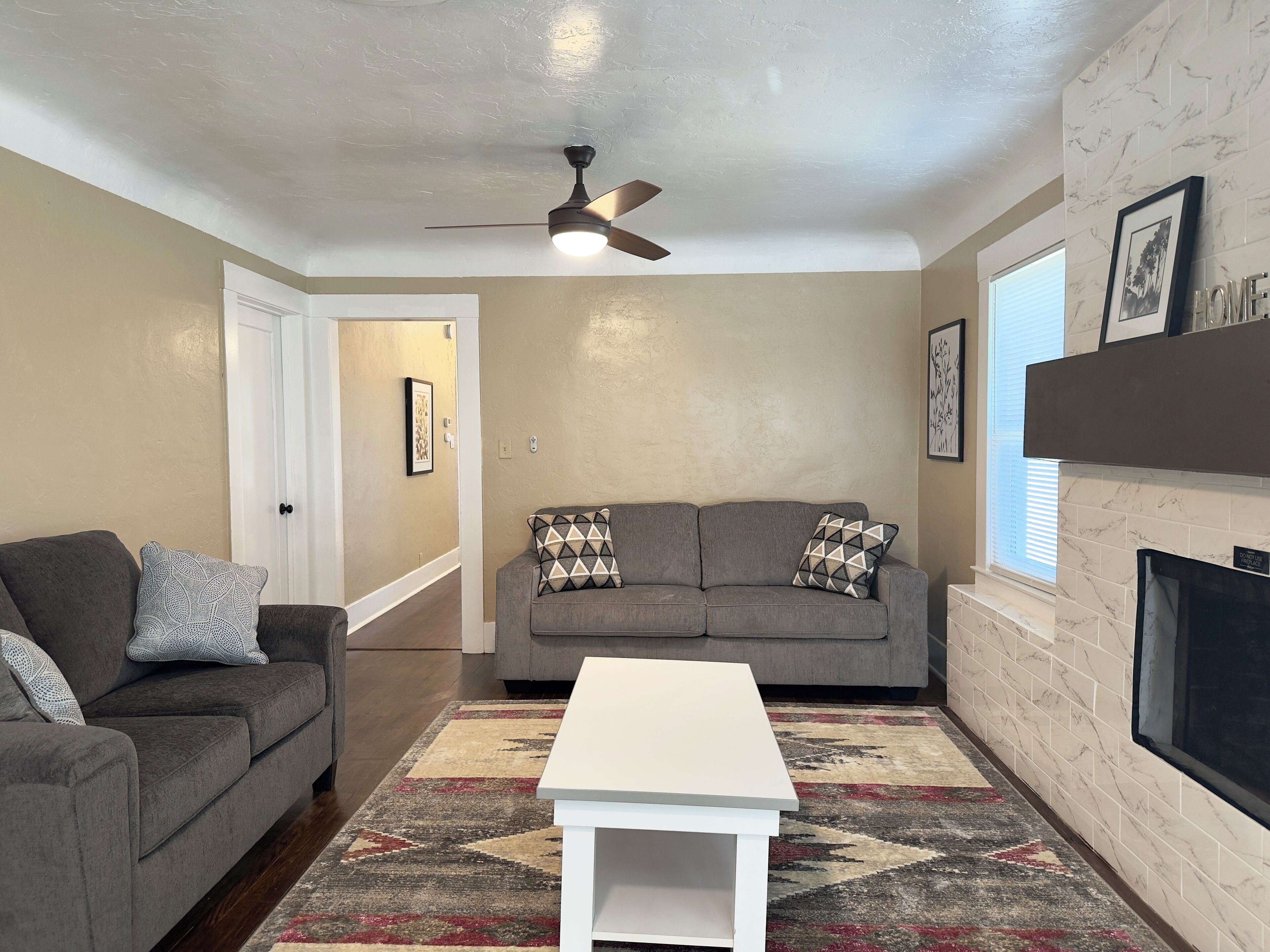 A living room with a gray sofa, a white coffee table, and a patterned rug.