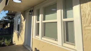 A house exterior with three large windows, a door, and a small outdoor light fixture.