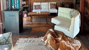 Ein rustikales Interieur mit freiliegenden Backsteinwänden, einem weißen Sofa, einem Holztisch und einer blauen Tür.