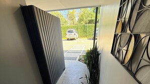 A hallway with tiled flooring, a metal gate, and a wall with a geometric pattern. - 5 minutes from Airport | Transfer ($) | Pool | Gym | Full condo (Provincia de Alajuela)
