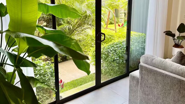 Un salon moderne doté d’une grande porte-fenêtre coulissante donnant sur un jardin.