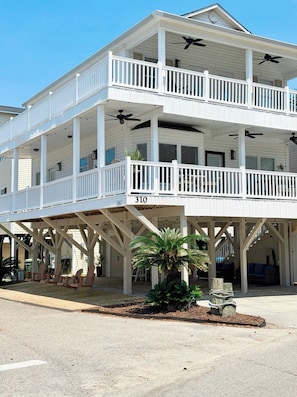 A multi-story building with balconies, outdoor seating, and a palm tree.