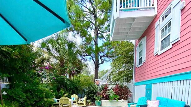 A backyard with a swimming pool, blue lounge chairs, and a red house.