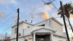 Un edificio de dos pisos con fachada blanca, base de piedra y un balcón.