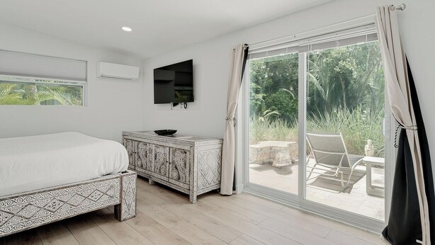 A bedroom with a bed, a TV, a cabinet, and a sliding glass door to a patio.