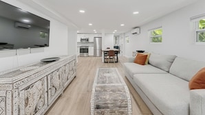 A modern living room with a sofa, a patterned coffee table, and a TV.