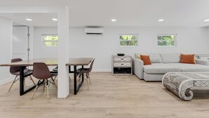 A modern living room with a sofa, a dining table with chairs, and a small side table.