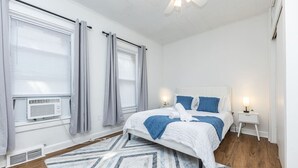 A bedroom with a bed, bedside tables, a ceiling fan, and a window with curtains. - Broadway Vibes Only 1BR  2 Beds  Best Location (Somerville)