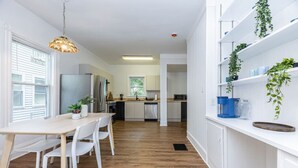 A modern kitchen with white cabinetry, a wooden dining table, and chairs. There is a hanging light fixture above the table. - Broadway Vibes Only 1BR  2 Beds  Best Location (Somerville)