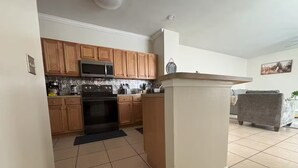 A modern kitchen with wooden cabinets, a microwave, and a stove. - 3 Bedrooms Condos at Cottages Oakleaf (Orange Park)