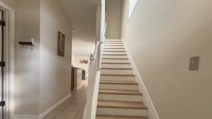 A clean, modern hallway with a staircase leading to another level. - 3 Bedrooms Condos at Cottages Oakleaf (Orange Park)