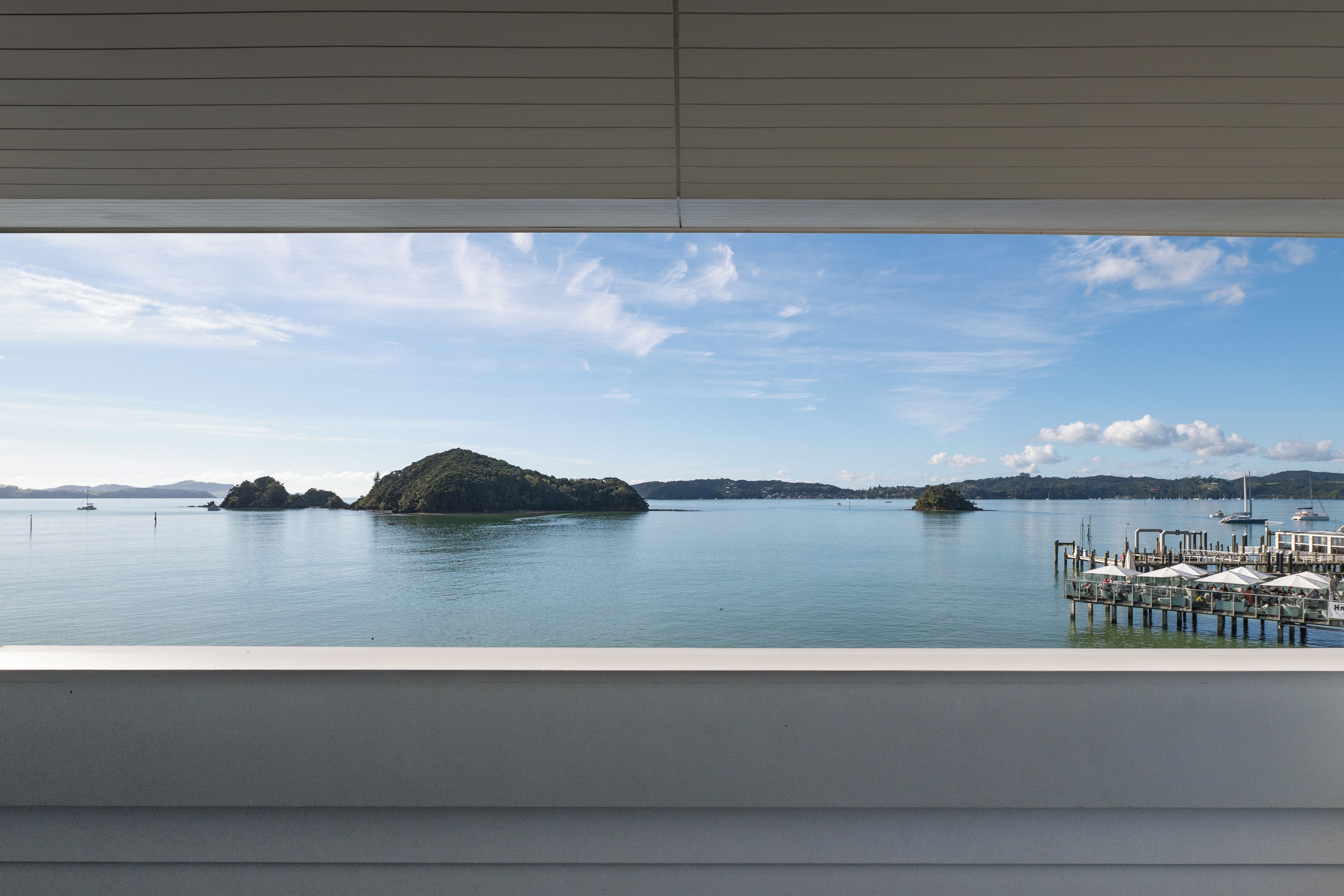 Vista de un cuerpo de agua tranquilo con varias islas pequeñas, un muelle con sombrillas y un cielo despejado.