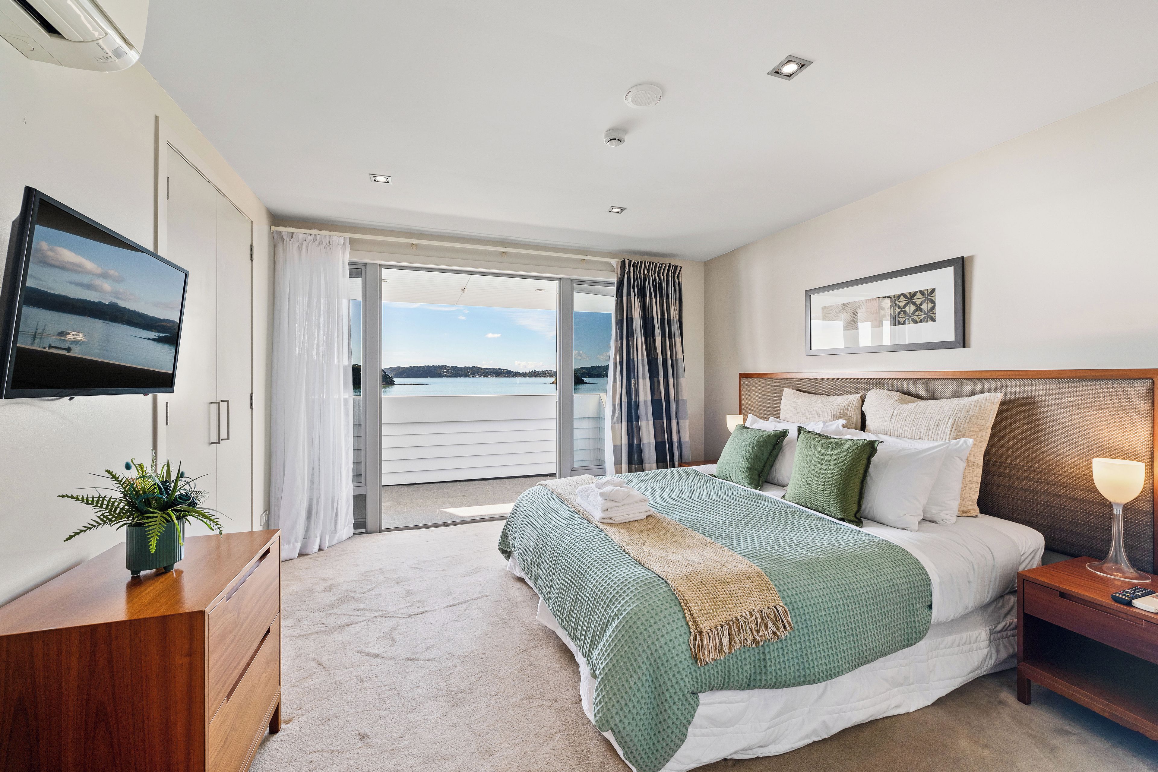Un dormitorio moderno con una cama grande, un televisor y vista al mar.