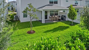 A modern two-story house with a covered patio and a well-maintained lawn.