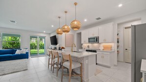 A modern kitchen with white cabinetry, a central island, and pendant lighting.