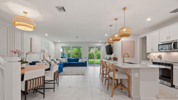 A modern kitchen with white cabinetry, a central island, and pendant lighting.