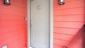 A door with a 'C' on it, flanked by two black lantern-style lights, and a small mailbox to the left.