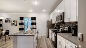 A modern kitchen with white cabinets, stainless steel appliances, and a central island.