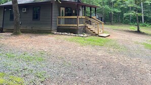 A cabin with a porch and a staircase leading to the entrance. - Peaceful cozy cabin in the woods (Murphy)
