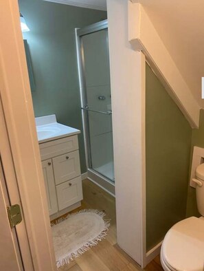 A small bathroom with a shower, toilet, and sink.